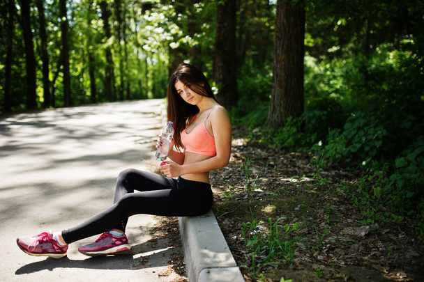 Fitness sport girl in sportswear sitting at road in park with wa - Foto, imagen