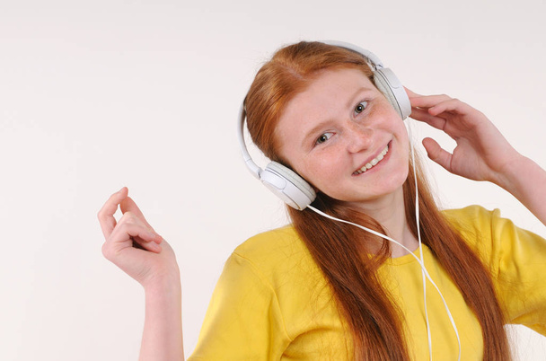 Beautiful young red hair girl with headphones relaxing by listening music - Fotografie, Obrázek