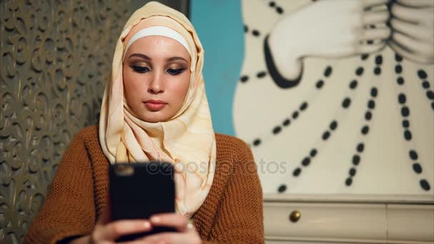Nowoczesna kobieta Emiraty w hidżab komunikuje się na jej telefonu komórkowego online z przyjaciółmi - Materiał filmowy, wideo