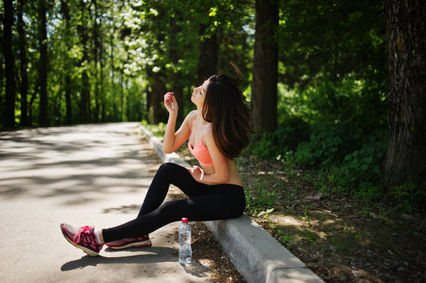 Fitness sport girl in sportswear sitting at road in park with wa - Foto, afbeelding