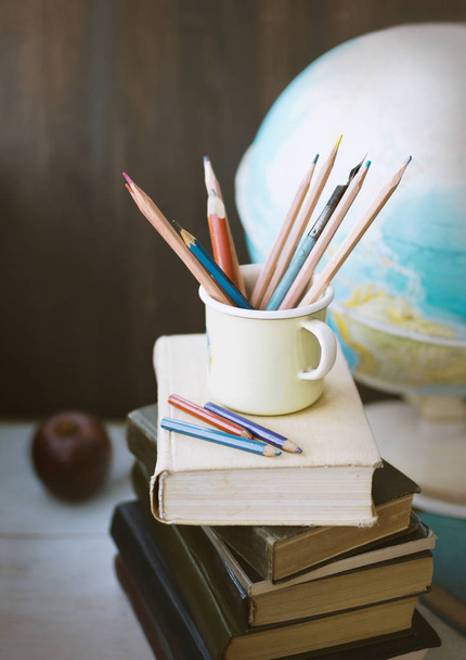 Lápices en la taza en la pila de libros y el globo escolar, de vuelta a la escuela naturaleza muerta, la educación
 - Foto, Imagen