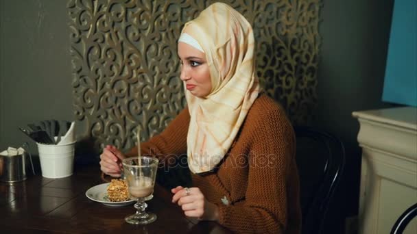 Moderni musliminainen syö jälkiruokaa ja juo suklaacocktailin kahvilassa.
 - Materiaali, video