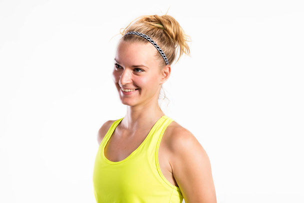 Attractive young fitness woman in yellow tank top. Studio shot. - Фото, зображення