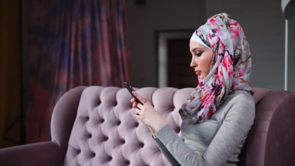 Modern Arab nő ül a kanapén és beszélgetni egy barátjának a telefon - Felvétel, videó