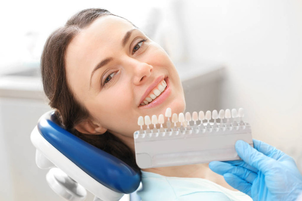 Dentist checking and selecting color of young woman's teeth - Foto, immagini