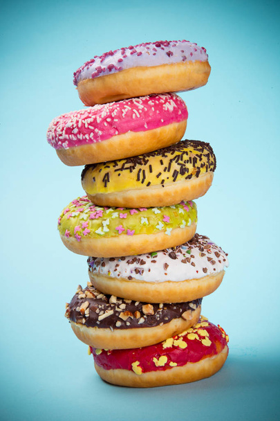 Donuts glazed with sprinkles on pastel blue background. - Foto, afbeelding