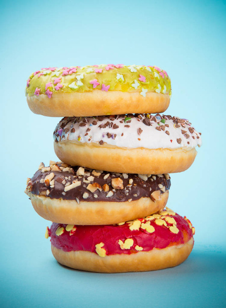 Donuts geglazuurd met hagelslag op pastel blauwe achtergrond. - Foto, afbeelding