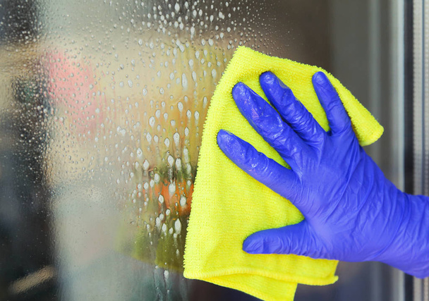 Woman cleaning a window with yellow cloth - Photo, Image