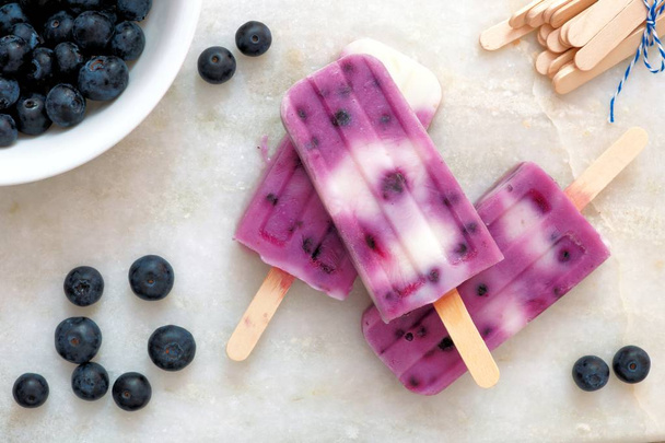 Blueberry vanilla popsicles on a white marble background - Foto, Imagen