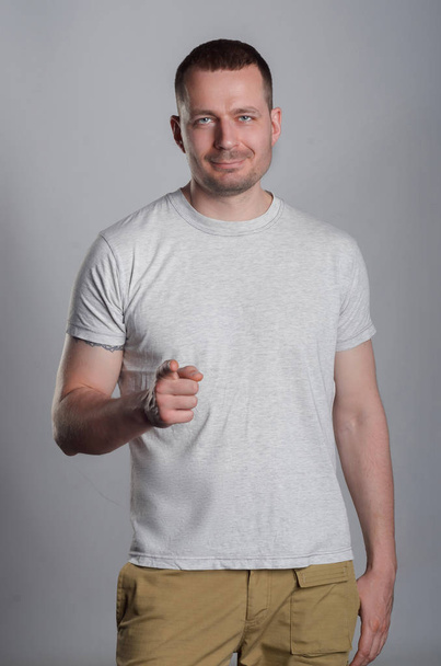 Un chico guapo y musculoso con una camiseta ligera y casual en un bac gris
 - Foto, Imagen
