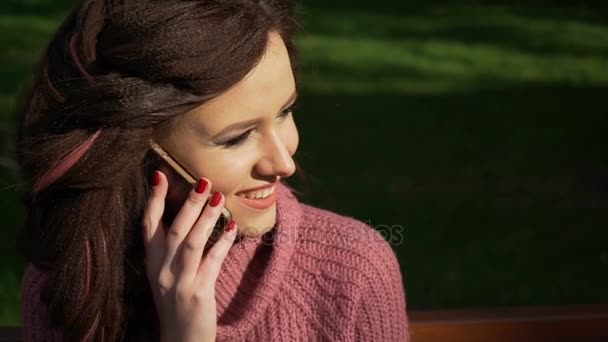 Gimbal shot of female teen girl talking on the phone sitting on bench in spring sunny day, uhd prores footage - Filmagem, Vídeo