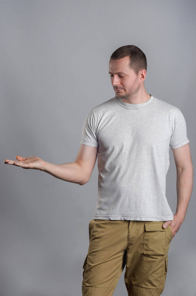 Un chico guapo y musculoso con una camiseta ligera y casual en un bac gris
 - Foto, Imagen