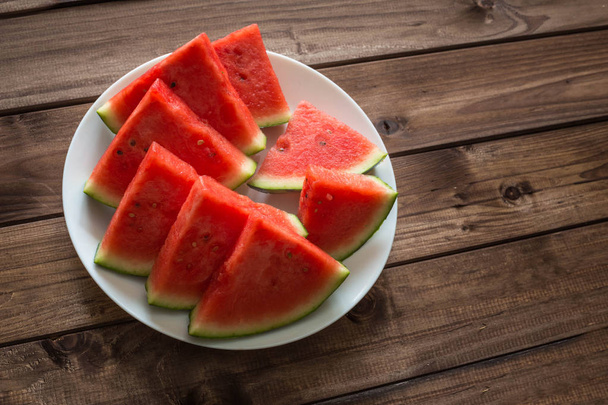 Juicy watermelon on a plate on the wooden background. - Φωτογραφία, εικόνα