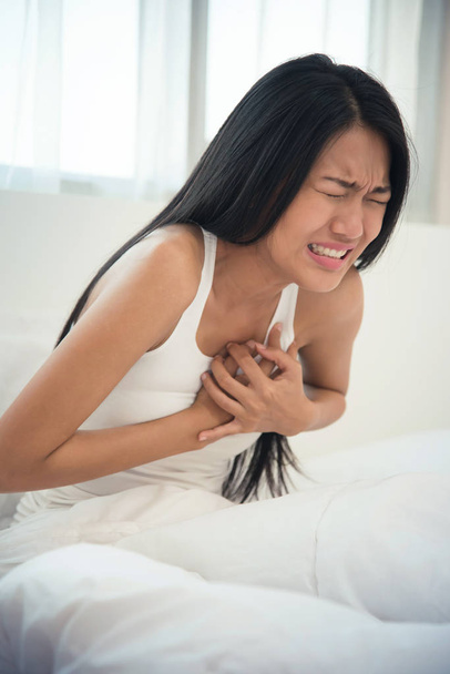 Asian woman having heart attack on her bed. copy space. - Foto, Imagen