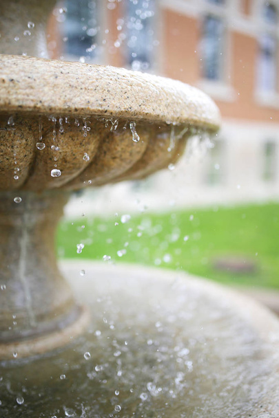 Close-up op waterdruppels druipend uit steen fontein - Foto, afbeelding