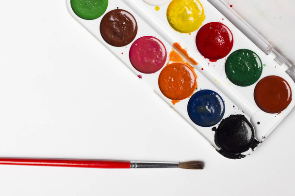 Різнокольорові акварельні фарби з пензлем на світло-сірому тлі. Об'єкти мистецтва
 - Фото, зображення