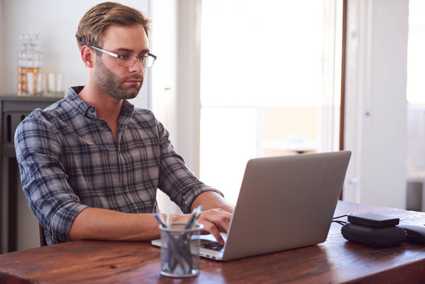 Ο σύγχρονος άνθρωπος που πληκτρολογείτε σε ένα φορητό υπολογιστή, ενώ κάθεται στο γραφείο - Φωτογραφία, εικόνα