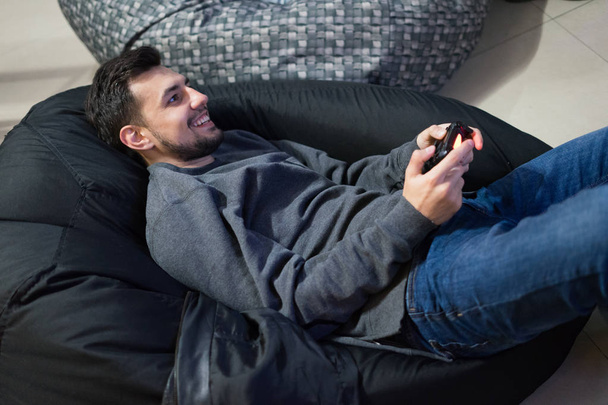 gamer jouer à des jeux vidéo avec joystick assis sur chaise sac haricot
 - Photo, image