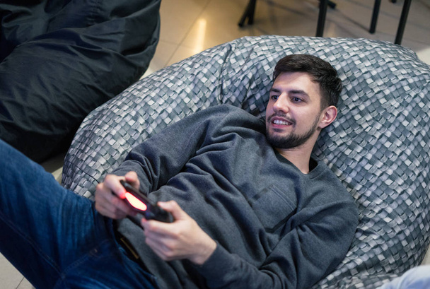 gamer pelaa videopelejä joystick istuu Bean laukku tuoli
 - Valokuva, kuva