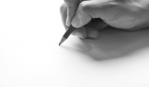 Pencil in hand on paper arts with shadows in black and white tone. - Фото, изображение