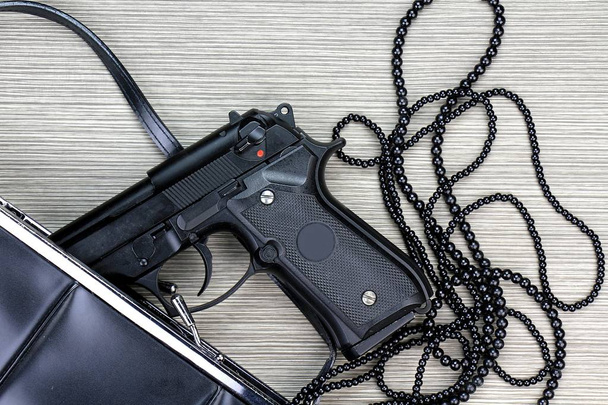 Bolso de mujer con pistola oculta, pistola y accesorios que caen del bolso de una mujer
. - Foto, Imagen
