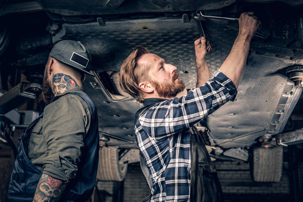 Dos mecánicos trabajando en garaje
 - Foto, Imagen