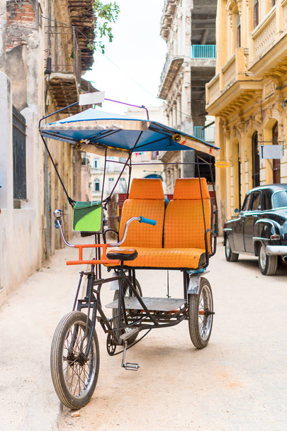Kubanisches Taxifahrrad vor bunten Kolonialhäusern geparkt - Foto, Bild
