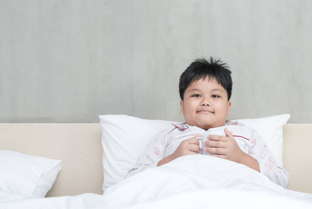 fat boy with milk cup on bedroom - Photo, Image