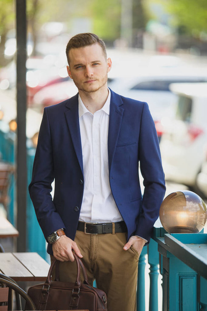 Businessman in classic vest against row of suits on the street. A young stylish man in a jacket. Advertising photo - Fotó, kép