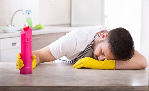 Man holding cleaning product and falling asleep - Foto, imagen