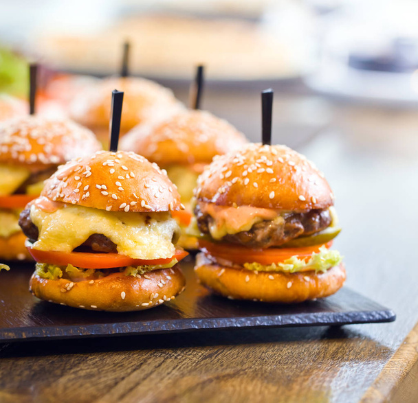  Burgers on wooden table in restaurant . - Фото, зображення
