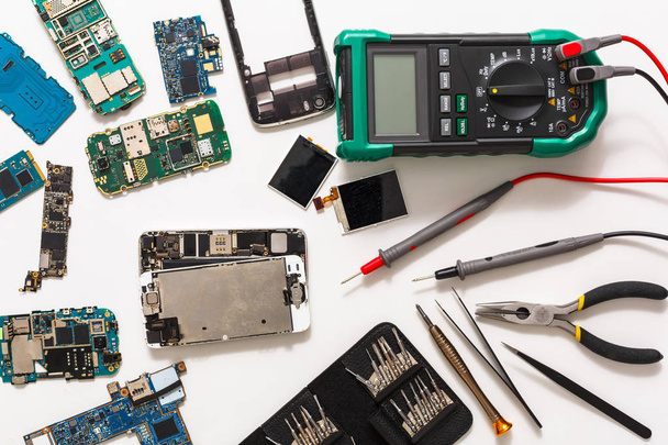 Multimeter and broken mobile electronics at repair shop - Zdjęcie, obraz