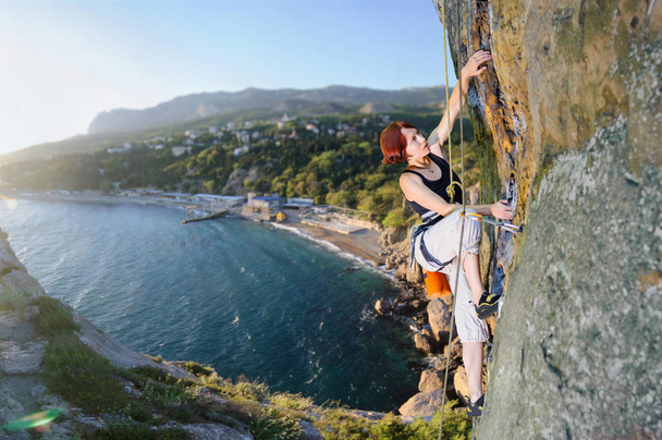 Female climber climbing with rope on a rocky wall - Photo, Image