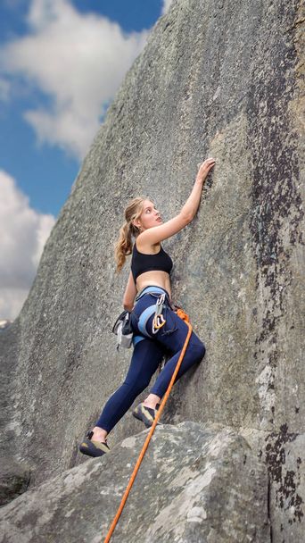 Kletterin klettert mit Seil an Felswand - Foto, Bild