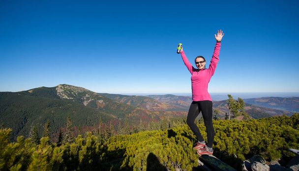 Молодая счастливая женщина-туристка на вершине горы
 - Фото, изображение