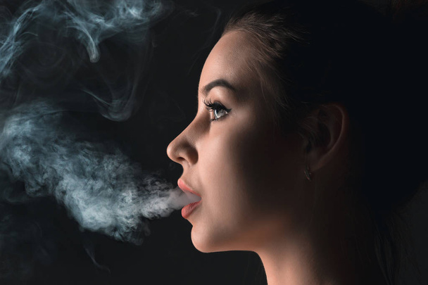 The face of vaping young woman at black studio - Foto, immagini