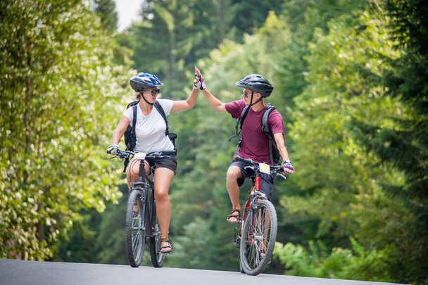 happy couple ride on a mountain asphalt road on bikes - Photo, Image