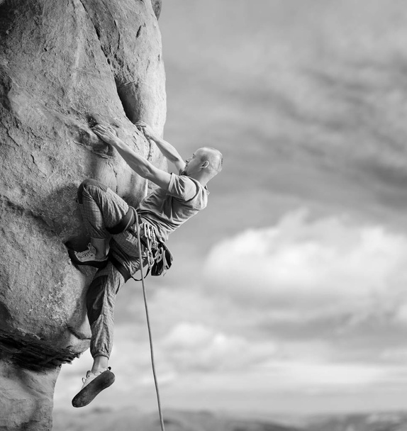 Escalador masculino escalando roca grande en la naturaleza con cuerda
 - Foto, imagen