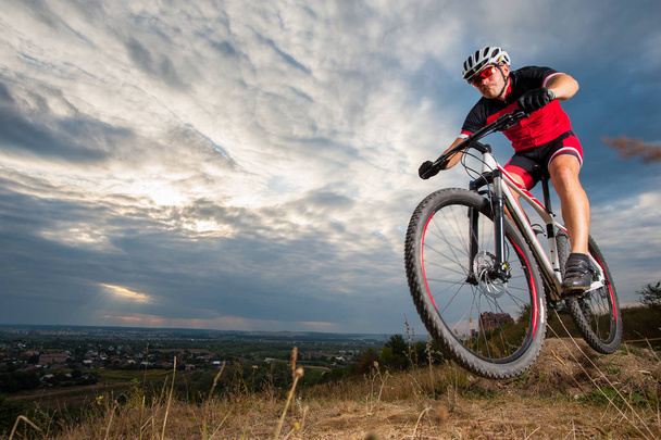 Mountain cyclist riding donwhill against blue evening sky - Photo, Image
