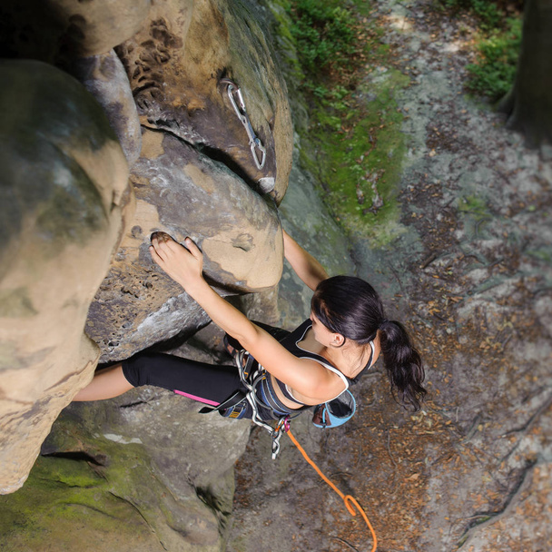 Mujer escaladora escalando roca grande en la naturaleza con cuerda
 - Foto, Imagen