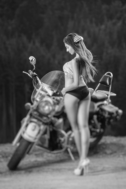 Jonge mooie sexy meisje permanent door de motorfiets - Foto, afbeelding