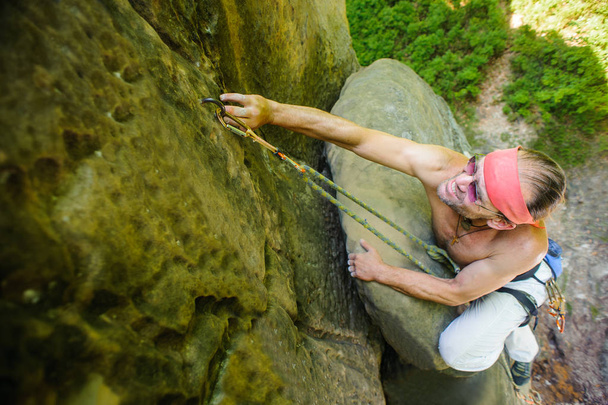 Masculino escalador de rocha escalada com corda em uma parede rochosa
 - Foto, Imagem