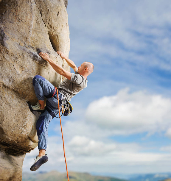 Scalatore maschio arrampicata grande masso in natura con corda
 - Foto, immagini