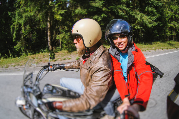 Pyöräilijä ajaa moottoripyörällään tiellä matkustajan kanssa
 - Valokuva, kuva
