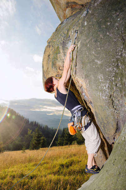Θηλυκό ορειβάτης αναρρίχηση με σχοινί σε έναν βραχώδη τοίχο - Φωτογραφία, εικόνα