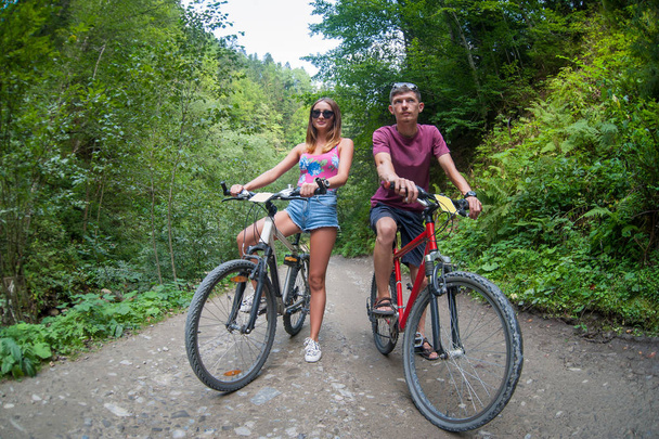 couple heureux rouler sur une route asphaltée de montagne sur les vélos
 - Photo, image