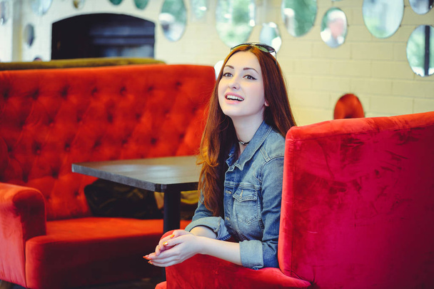 Появившаяся молодая арабка на красном диване в кафе подглядывает
 - Фото, изображение