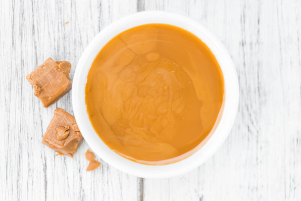 Portion of Caramel Sauce on wooden background  - Photo, Image