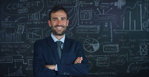 Портрет бизнесмена, учителя маркетинга, рисует график успеха на черной доске, на черном фоне. Концепция: карьерный рост, график роста, успешный человек, маркетинг, идеи, финансы
. - Фото, изображение