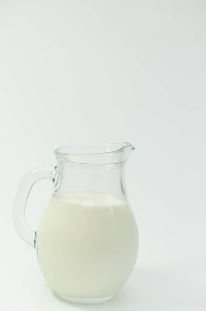 Fresh cow milk in a jar on a light background. - Фото, изображение